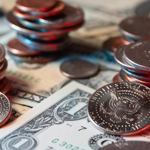 Dollar coins on US dollar banknotes. Piled up coins symbol for prosperity. Half dollar coins in front.
